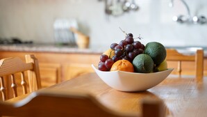 Een schaal fruit op een houten tafel in een keuken.