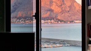 A coastal view with a mountain, a marina, and a cityscape.