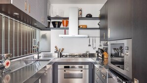 A modern kitchen with stainless steel appliances, a central island, and a variety of utensils and cookware.