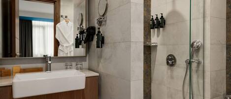 A modern bathroom with a sink, mirror, and shower.