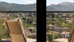 Two beige chairs with a view of a town and mountains through a window. - La Quinta by Wyndham Batumi (Batumi)