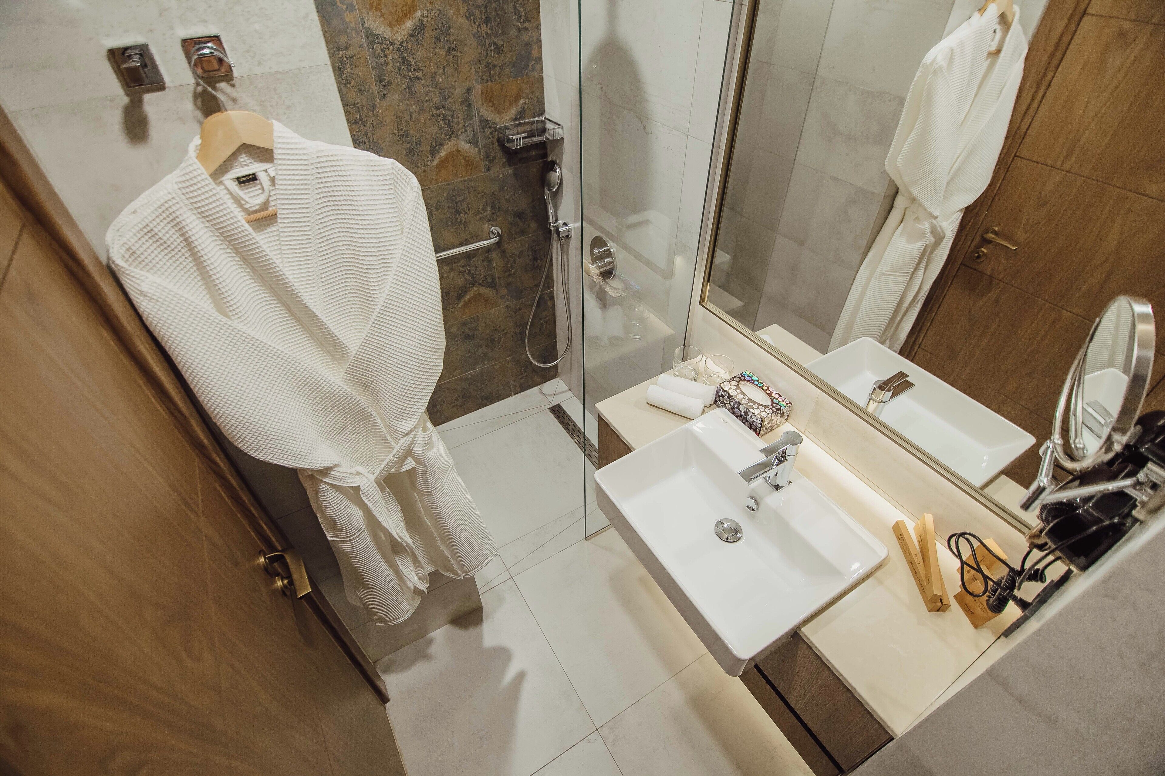 A modern bathroom with a glass shower enclosure, a white sink, and a mirror.