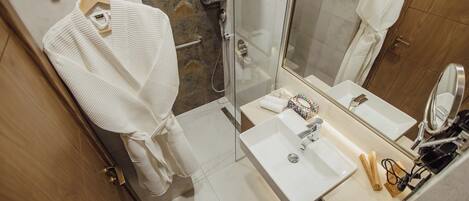 A modern bathroom with a glass shower enclosure, a white sink, and a mirror.