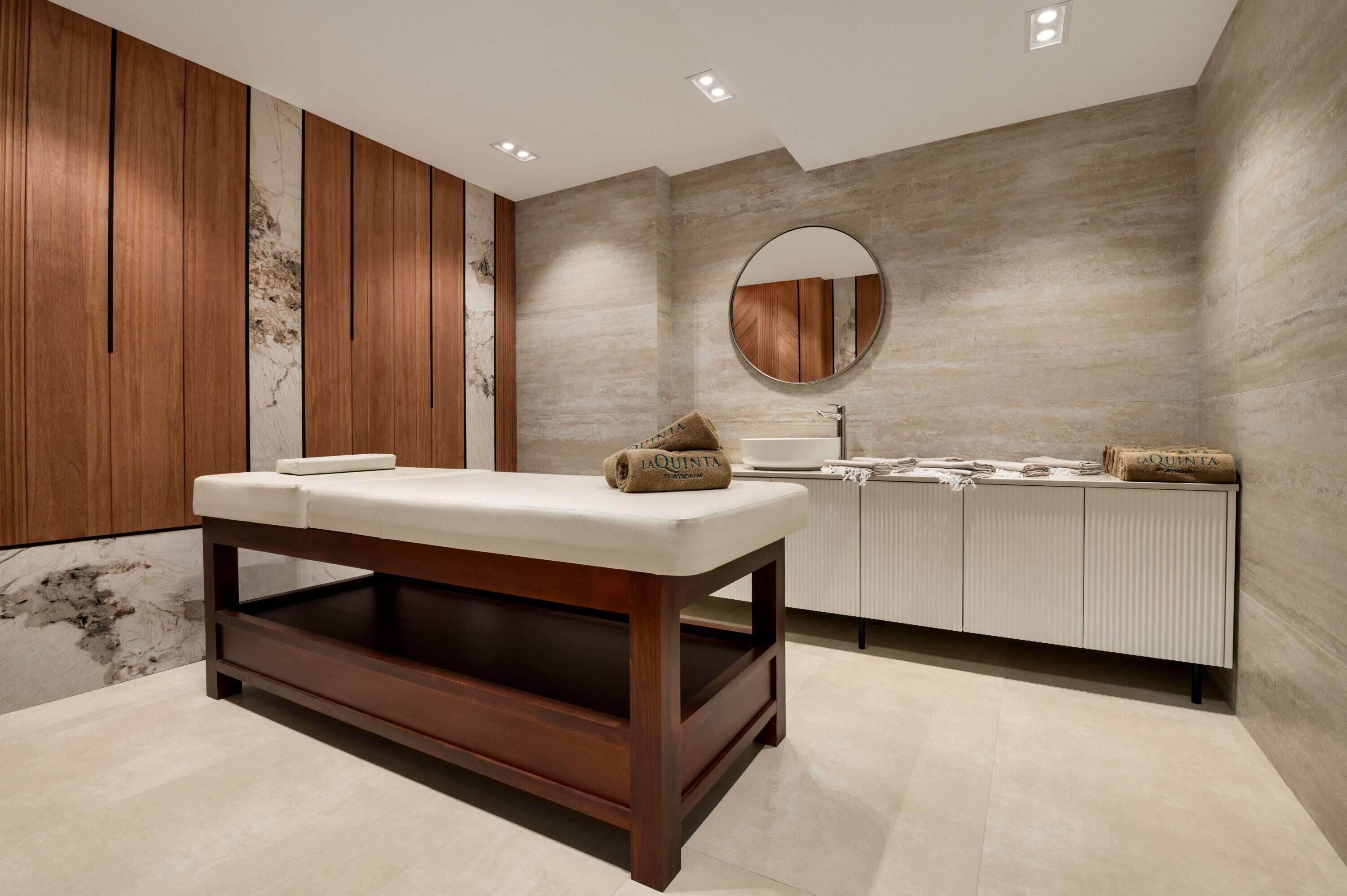 A modern bathroom with a wooden bench, a round mirror, and a tiled wall.