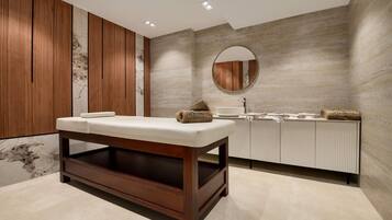 A modern bathroom with a wooden bench, a round mirror, and a tiled wall.