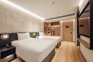 Camera d'albergo con due letti, un comodino con il telefono, uno specchio e un armadio.