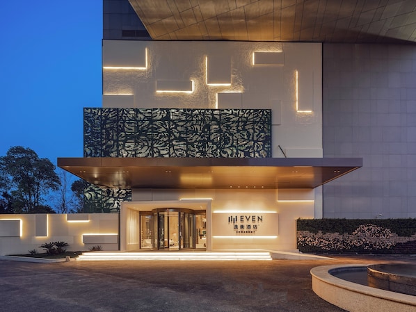 Una entrada de hotel moderna con un giratorio, patrones geométricos iluminados y un cartel que dice "EVEN".