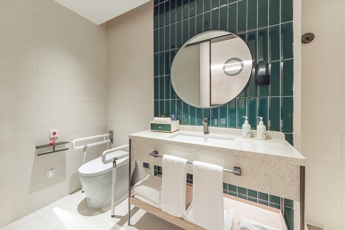 Ein modernes Badezimmer mit Toilette, Waschbecken mit Spiegel darüber und Handtuchhalter.