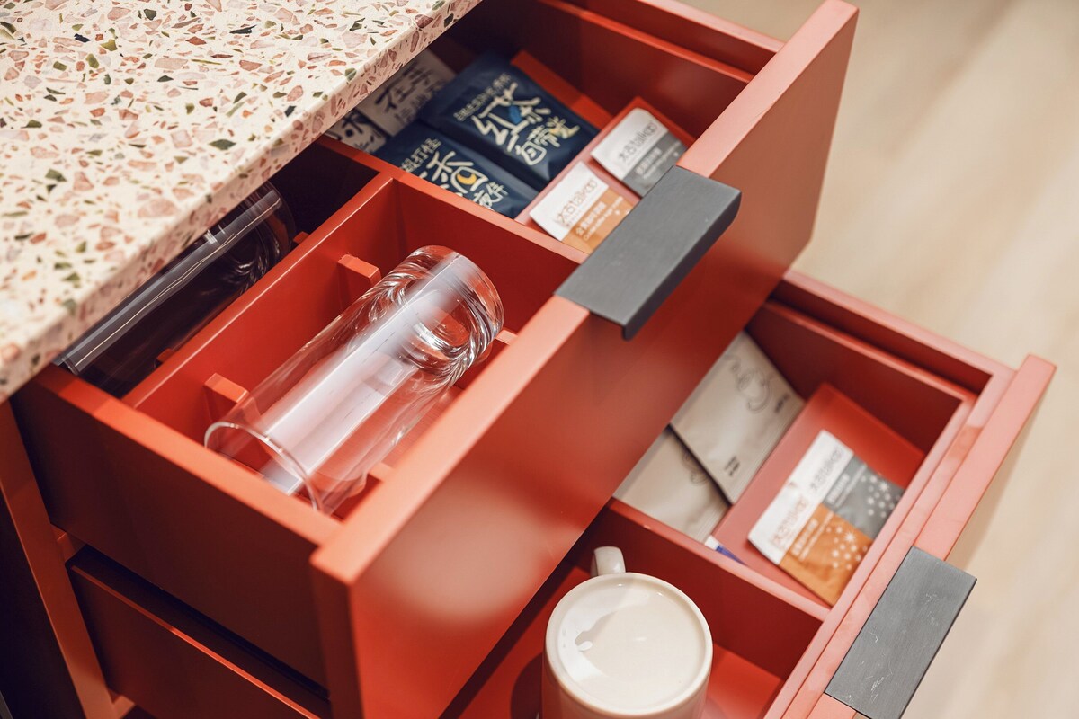 Eine Schublade mit einer klaren Glasflasche, einer Kaffeetasse und verschiedenen verpackten Gegenständen.