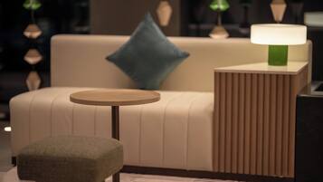 A modern living room with a sofa, a round table, and a lamp.