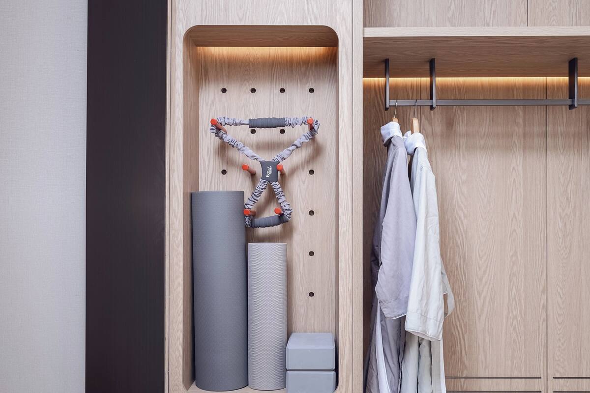 A wooden wardrobe with a built-in storage unit containing a yoga mat, a textured mat, and a small box.