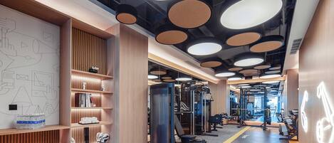 A gym with exercise equipment, wooden walls, and a ceiling with circular lights.