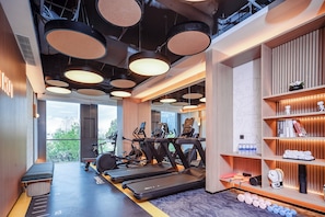 Un gimnasio moderno con cintas de correr, elípticas y pesas libres.