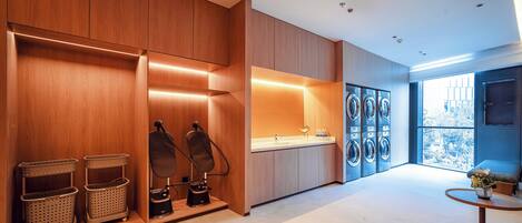 A modern laundry room with wooden cabinets, a washing machine, and a sink.