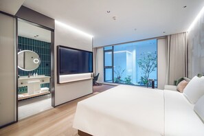 A modern hotel room with a large bed, a flat-screen TV mounted on the wall, a bathroom with a glass partition, and a view of the outdoors. - EVEN Hotel Shanghai Jinqiao by IHG (Shanghai)