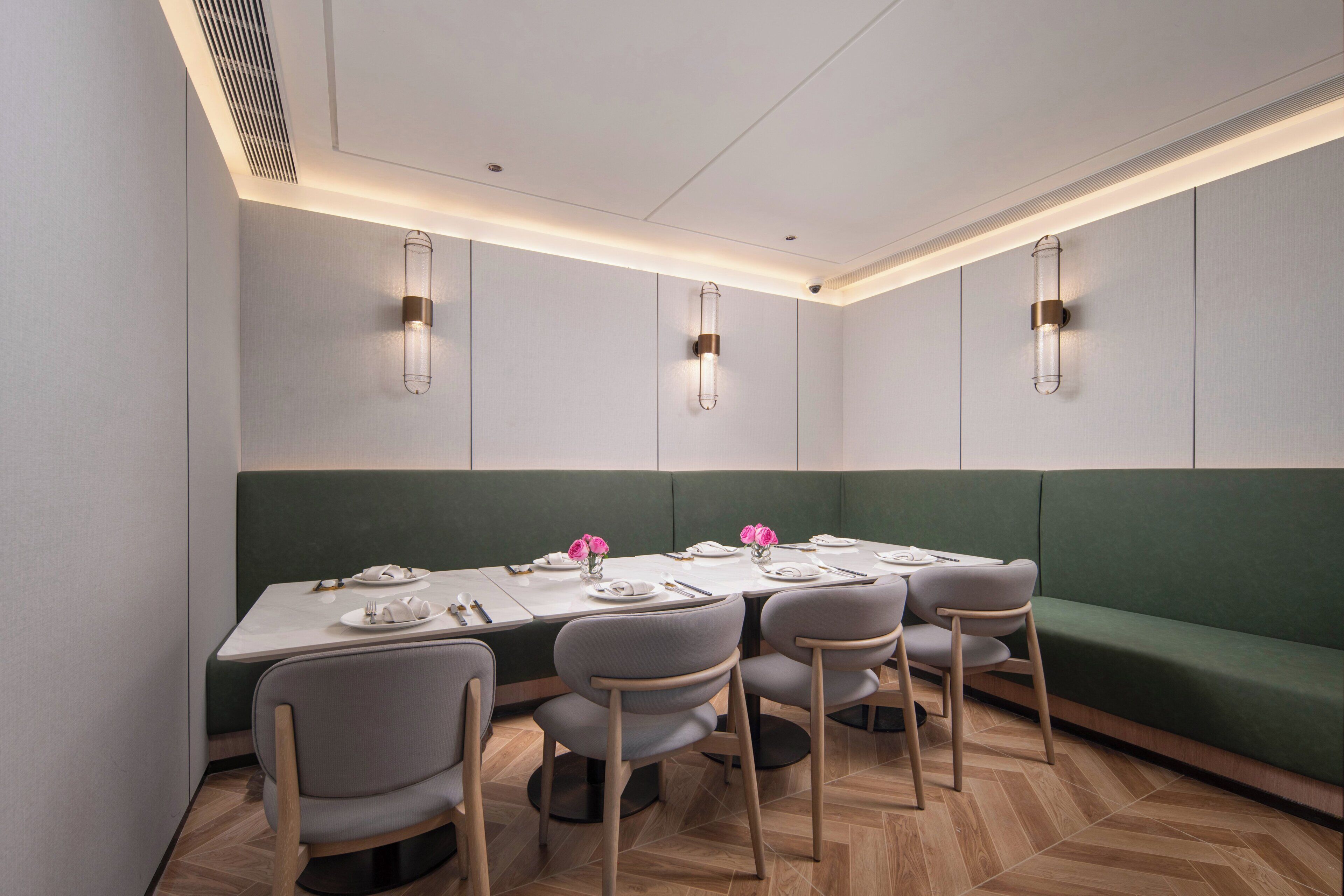 A dining area with a long table, green cushioned bench, and modern chairs.