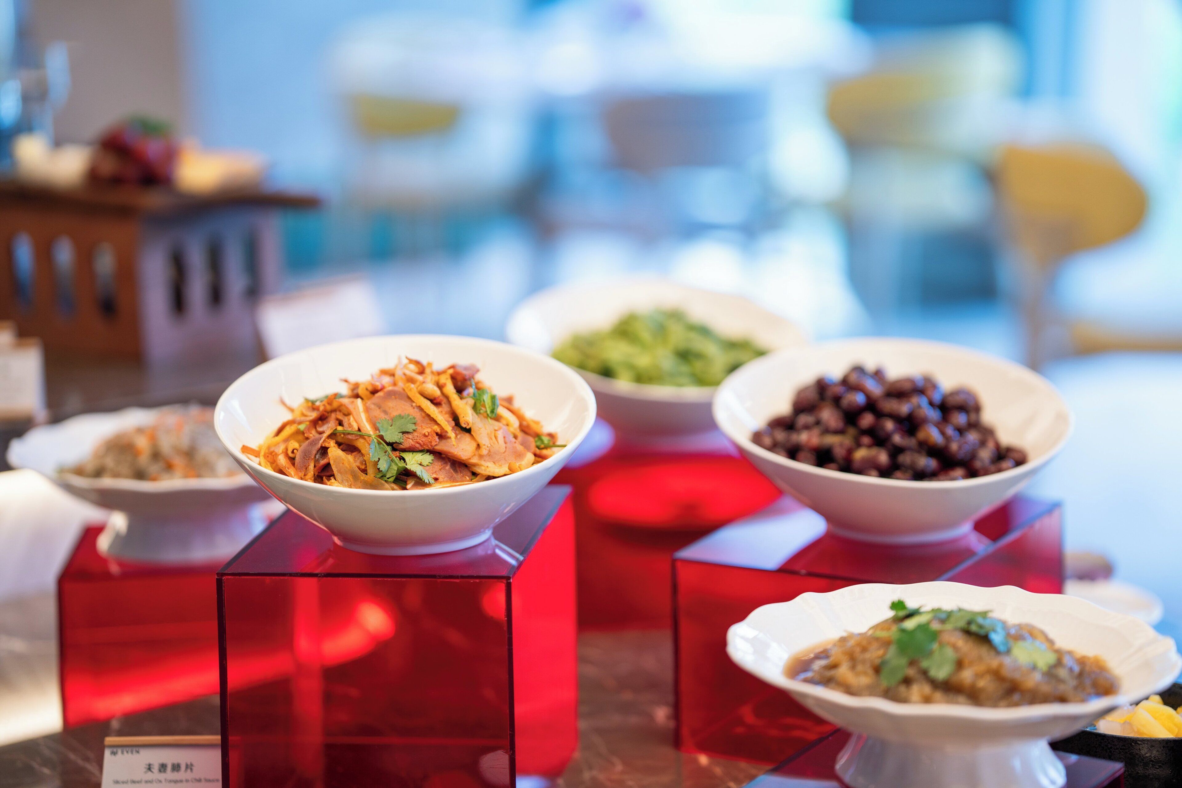 Une table à manger sur laquelle sont présentés différents plats, disposés sur des présentoirs rouges.