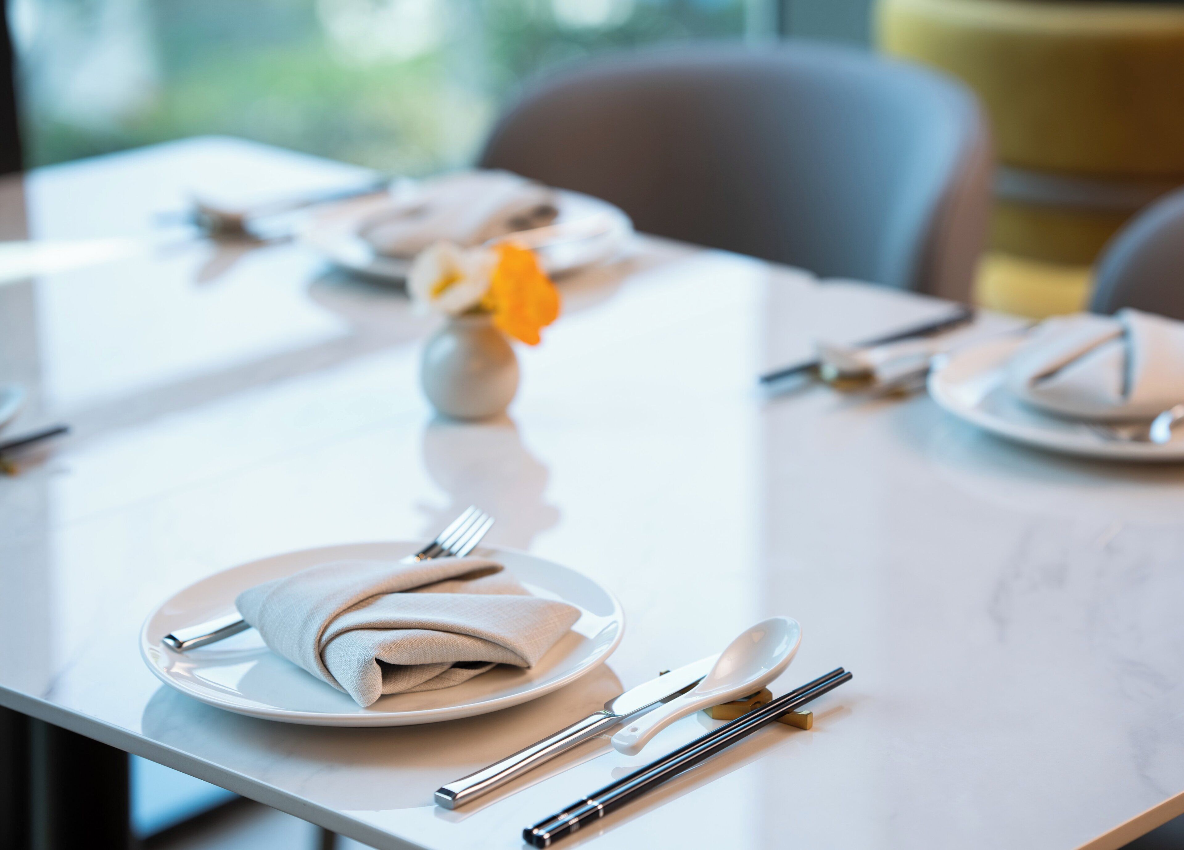 A neatly set dining table with plates, cutlery, and a folded napkin.