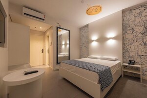 Quarto com cama, mesa de cabeceira, espelho, quadro na parede e ar condicionado.