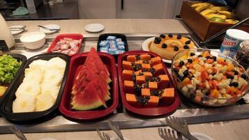 Monipuolinen buffet, jossa on tarjolla erilaisia ruokia, kuten hedelmiä, vihanneksia ja jälkiruokia.