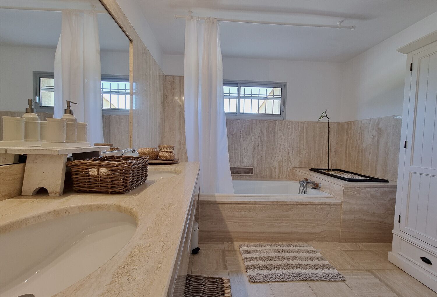 A modern bathroom with a large bathtub, a separate shower area, and a vanity with a mirror.