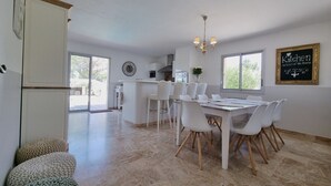 A modern kitchen with a dining area, featuring a large island, white cabinetry, and a chandelier. - Jardin d'Uzès walking distance village (Saint-Quentin-la-Poterie)
