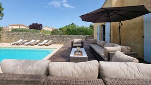 A pool area with lounge chairs, a sofa, and a table with a bottle and glasses. - Jardin d'Uzès walking distance village (Saint-Quentin-la-Poterie)