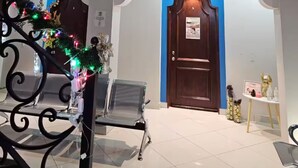 A hotel lobby with a high ceiling, a central wooden door, and a seating area with metal chairs. - Casa Real Hotel (Degollado)