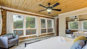 Une chambre avec un grand lit, un ventilateur de plafond et une vue sur l’extérieur.