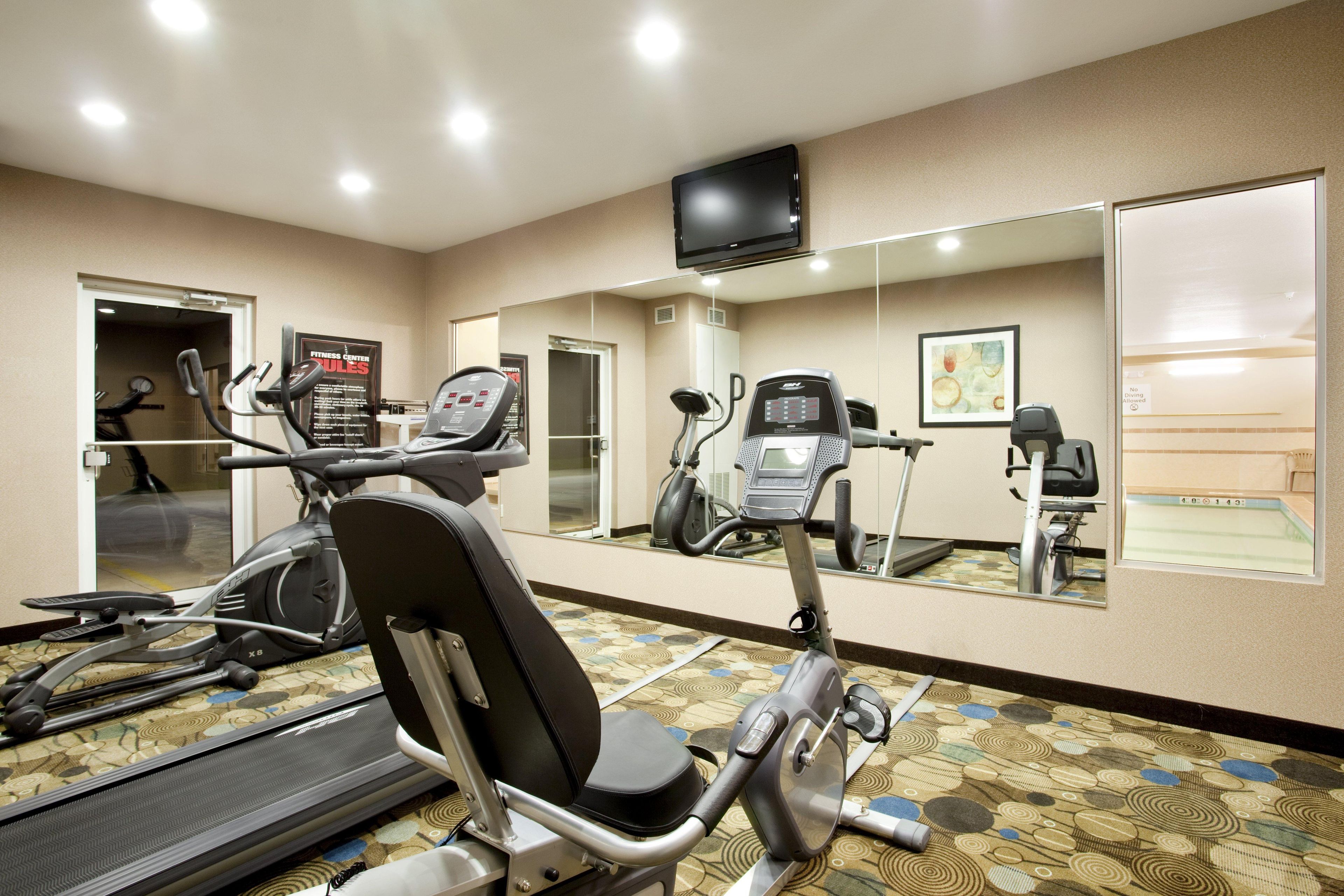 A gym with exercise equipment, a treadmill, and a mirrored wall.