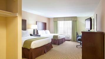 A hotel room with two beds, a desk, a chair, a television, and a window with curtains.