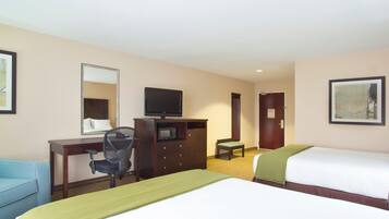A hotel room with two beds, a desk with a chair, a television, a mirror, and a door.