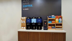 Um espaço com estação de café, vários distribuidores, ponto de água quente e diversos produtos de café nas prateleiras.