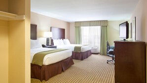 Quarto de hotel com duas camas, uma escrivaninha, uma cadeira, televisão e janela com cortinas.