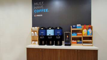 A coffee station with multiple coffee dispensers, a hot water station, and various coffee products on shelves.