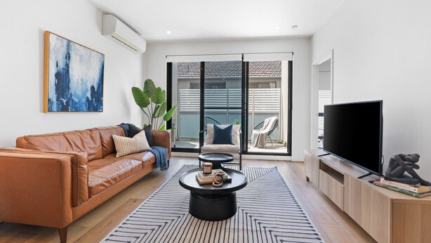 A modern living room with a leather sofa, a coffee table, and a TV. - Urban Living at Its Best (Carnegie)