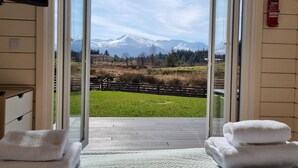 A room with a view of a mountain range, a wooden deck, and a fire extinguisher on the wall. - Toradh Cabin (Spean Bridge)