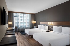Une chambre d’hôtel avec deux lits, un bureau, une chaise et un téléviseur.