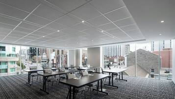 Une salle de conférence moderne, dotée d’un plafond haut, de grandes fenêtres et offrant une vue sur la ville.