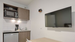 A compact kitchen with a microwave, coffee maker, and dishwasher. A flat-screen TV is mounted on the wall. - Cosy studio proche RER, idéal pour visiter Paris (Nogent-sur-Marne)