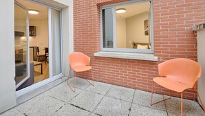 A small patio area with two orange chairs, a window, and a brick wall. -  À 3 km de la gare RER E | Accès rapide à Paris (Nogent-sur-Marne)