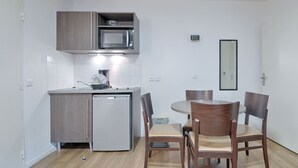 A compact kitchen with a microwave, sink, and a small refrigerator. There is a dining table with four chairs. - À 3 km de la gare RER E | Accès rapide à Paris (Nogent-sur-Marne)