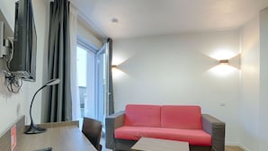 A modern living room with a red sofa, a wooden coffee table, a desk with a lamp, and a TV mounted on the wall. - À 3 km de la gare RER E | Accès rapide à Paris (Nogent-sur-Marne)