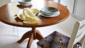 A round wooden dining table with two bowls and a fork, a yellow cloth, and a patterned chair. - UzuriBarossa, Tranquil guesthouse retreat in Lyndoch, Barossa Valley (Altona)