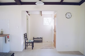 Enter a cozy space with a comfortable bench and chair, a small table, and a clock on the wall.
