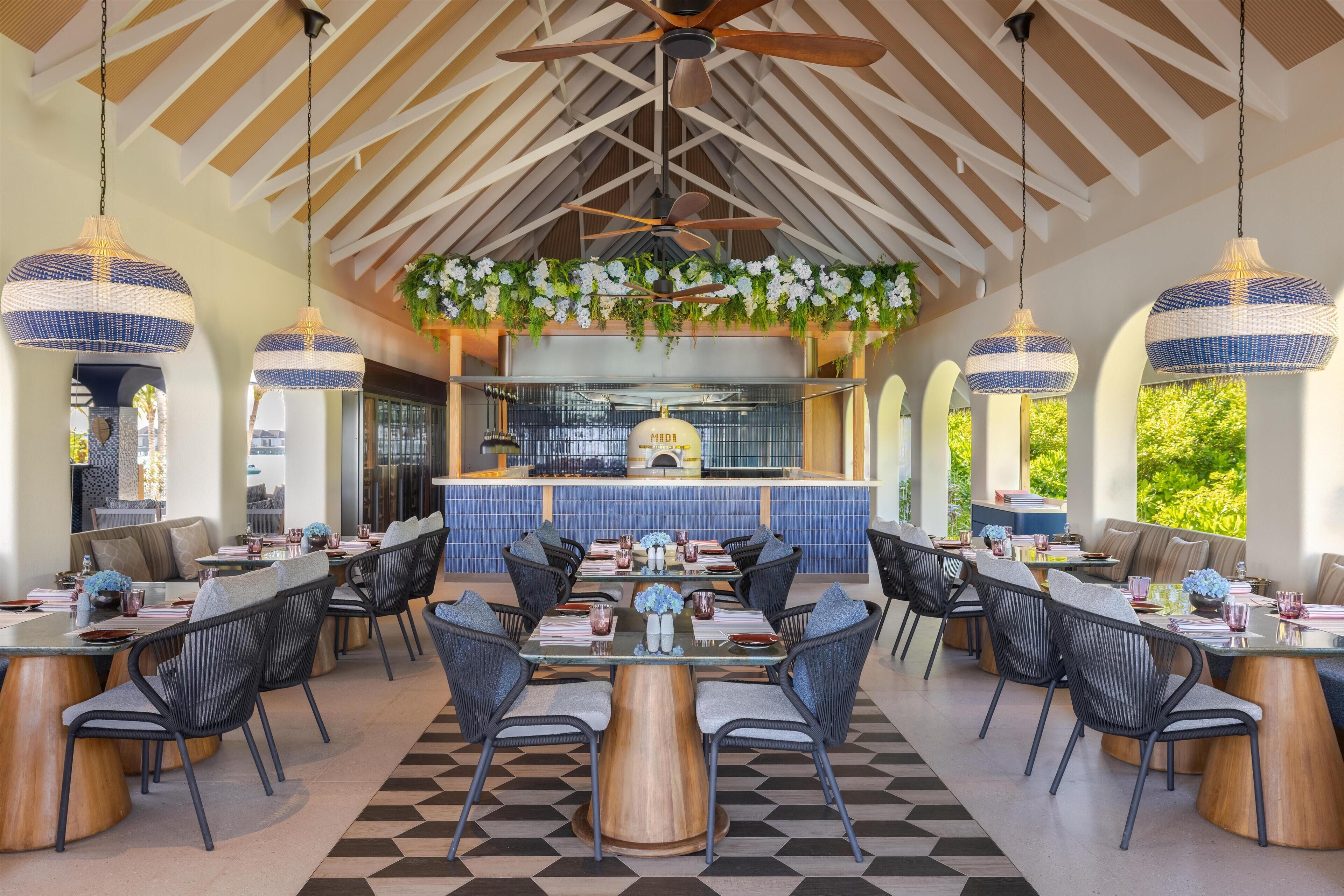 A spacious dining area with high ceilings, hanging pendant lights, and a central bar.