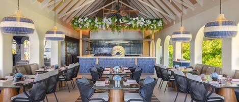 A spacious dining area with high ceilings, hanging pendant lights, and a central bar.