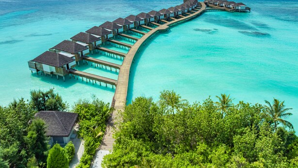 Een overwaterresort met meerdere bungalows verbonden door een houten looppad.