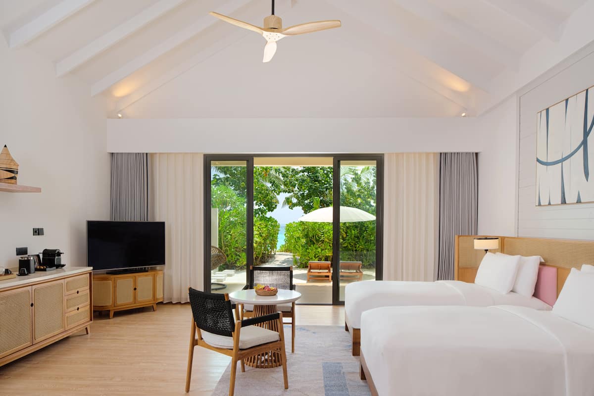 Une chambre d’hôtel avec un grand lit, une télévision, une table à manger et un balcon donnant sur l’extérieur.