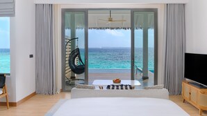 Een slaapkamer met een groot bed, een televisie en een balkon met uitzicht op de oceaan.